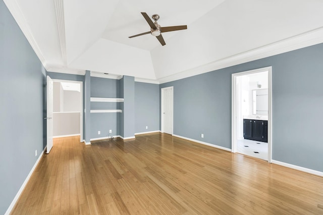 unfurnished bedroom featuring ensuite bath, a raised ceiling, crown molding, wood-type flooring, and vaulted ceiling