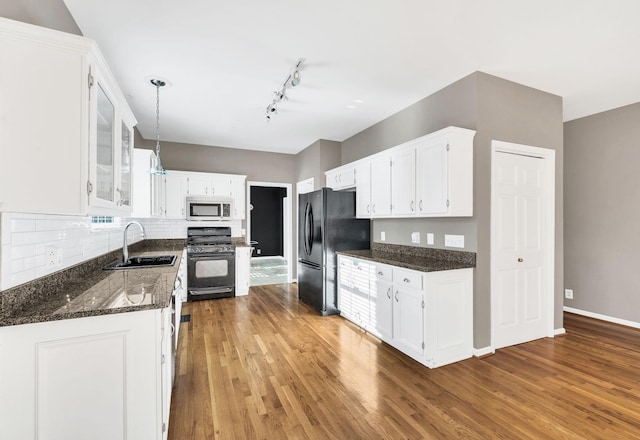 kitchen with sink, black appliances, decorative light fixtures, white cabinets, and light hardwood / wood-style floors