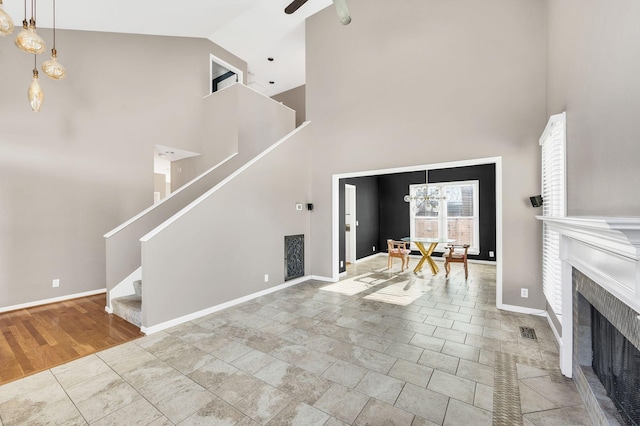 entryway with ceiling fan with notable chandelier and high vaulted ceiling