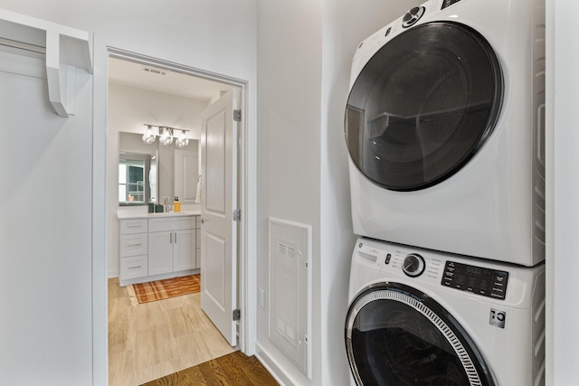 clothes washing area featuring wood-type flooring and stacked washer / dryer