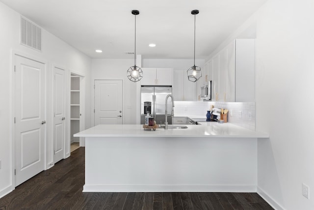 kitchen with kitchen peninsula, sink, decorative backsplash, appliances with stainless steel finishes, and white cabinetry