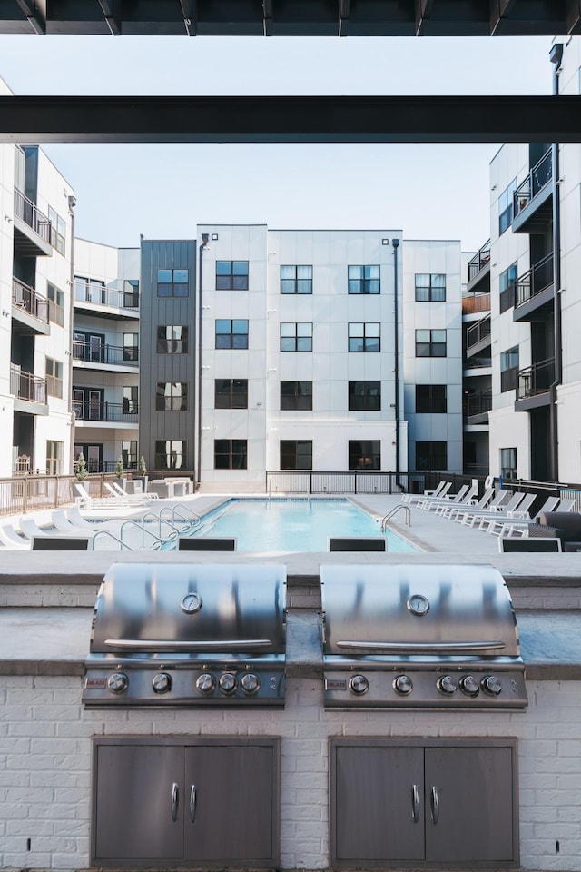 view of patio with area for grilling, a grill, and a community pool