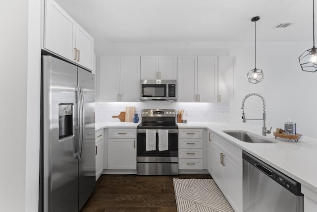 kitchen featuring stainless steel appliances, dark wood-type flooring, sink, pendant lighting, and white cabinetry