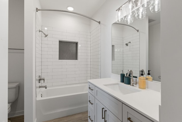 full bathroom featuring hardwood / wood-style floors, vanity, toilet, and tiled shower / bath