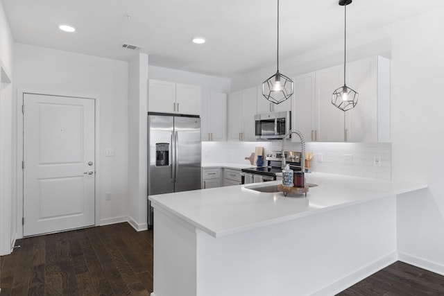 kitchen featuring kitchen peninsula, appliances with stainless steel finishes, backsplash, white cabinets, and hanging light fixtures