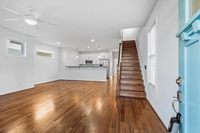 unfurnished living room featuring dark hardwood / wood-style floors, ceiling fan, and a healthy amount of sunlight