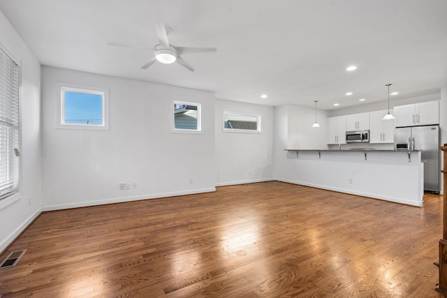 unfurnished living room featuring dark hardwood / wood-style floors, a wealth of natural light, and ceiling fan