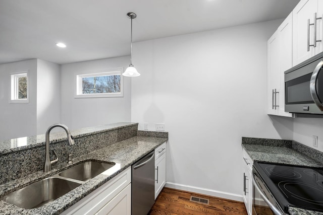 kitchen with white cabinets, appliances with stainless steel finishes, dark stone countertops, and sink