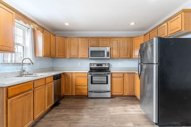 kitchen featuring hardwood / wood-style floors, ornamental molding, sink, and appliances with stainless steel finishes