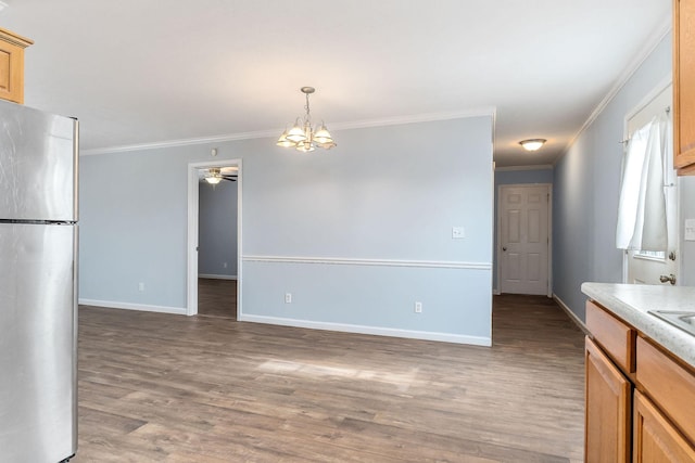 kitchen featuring hardwood / wood-style floors, pendant lighting, ceiling fan with notable chandelier, stainless steel fridge, and ornamental molding