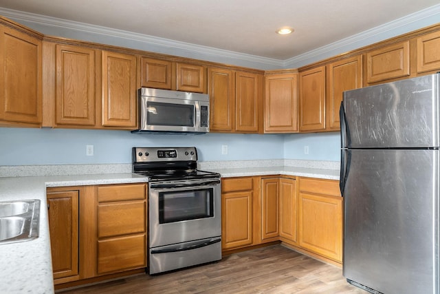 kitchen featuring wood-type flooring, stainless steel appliances, and ornamental molding