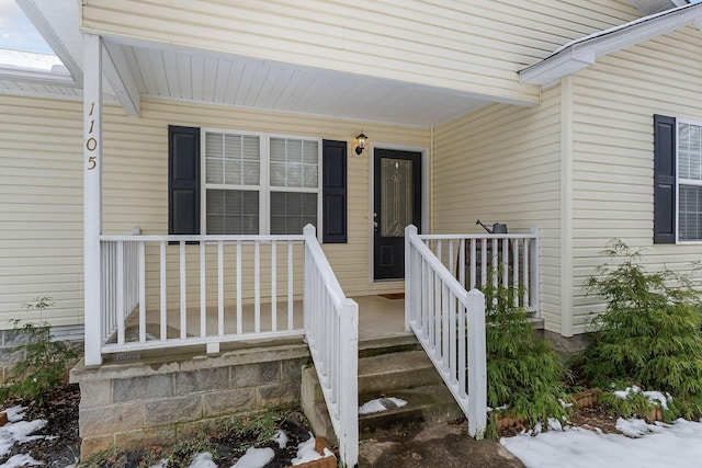 snow covered property entrance featuring covered porch