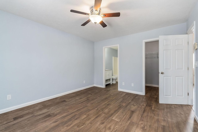 unfurnished bedroom featuring dark wood-type flooring, a walk in closet, ceiling fan, connected bathroom, and a closet