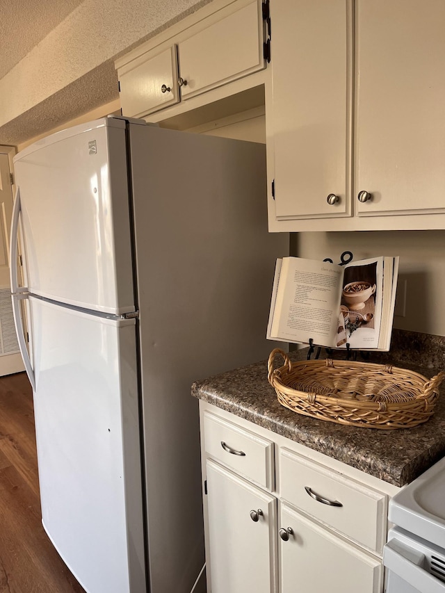 kitchen with white cabinetry, white fridge, and dark wood-type flooring