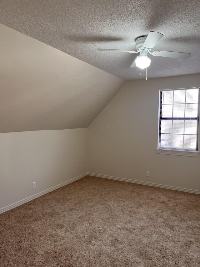 additional living space with ceiling fan, carpet flooring, vaulted ceiling, and a textured ceiling