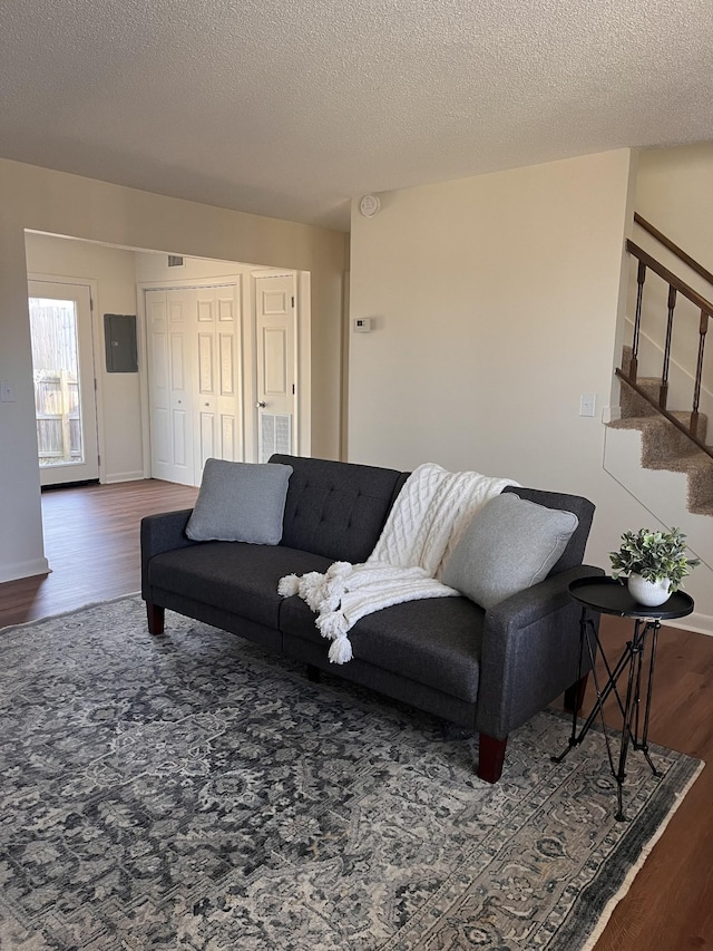 living room featuring dark hardwood / wood-style flooring, electric panel, and a textured ceiling