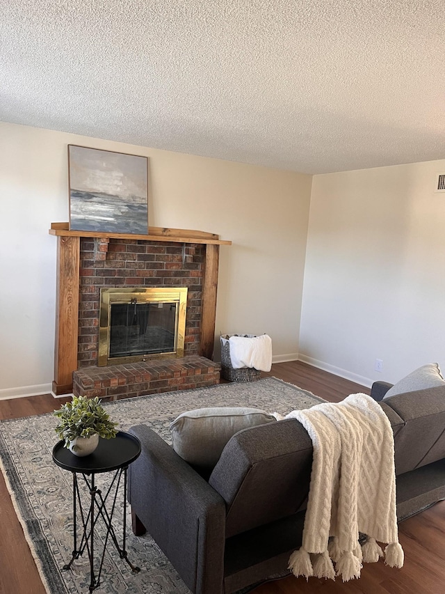 living room featuring dark wood-type flooring, a fireplace, and a textured ceiling