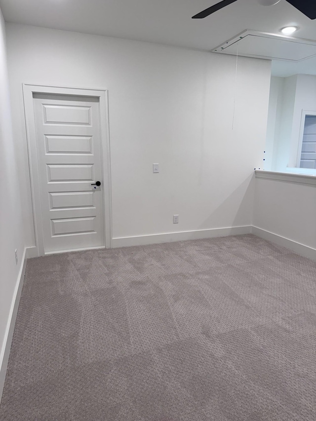 unfurnished room featuring baseboards, carpet floors, and attic access