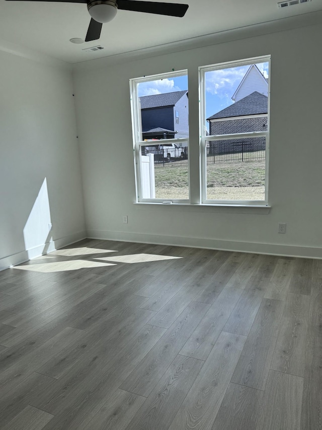 spare room featuring ceiling fan, wood finished floors, visible vents, and baseboards