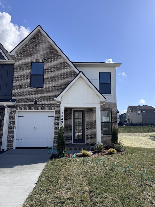 view of front of property featuring brick siding, board and batten siding, a front yard, a garage, and driveway