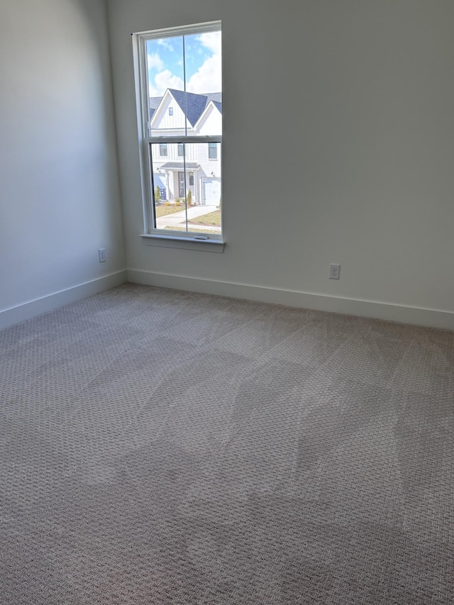 unfurnished room featuring light carpet and baseboards