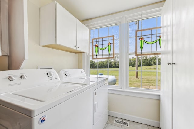 laundry room with cabinets, light tile patterned floors, and washing machine and clothes dryer