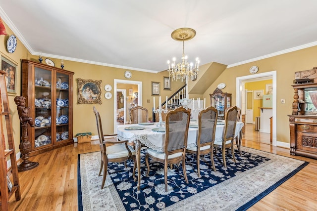 dining space with wood-type flooring, crown molding, and a chandelier