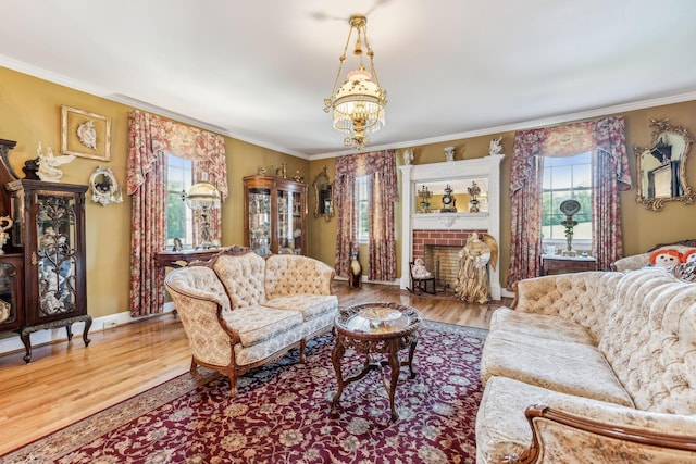 living room with a brick fireplace, light hardwood / wood-style flooring, a chandelier, and ornamental molding