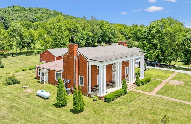 rear view of property featuring central air condition unit and a lawn