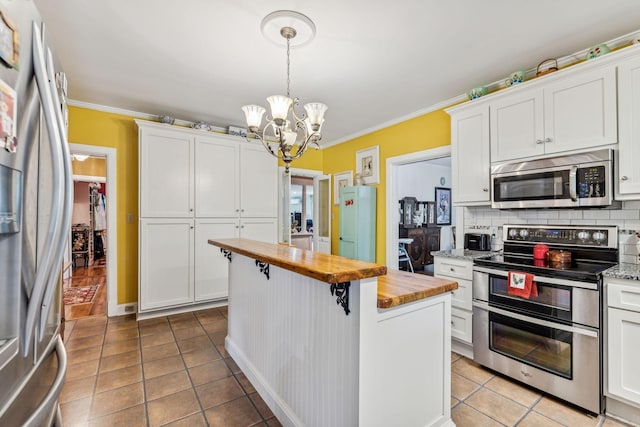 kitchen featuring backsplash, stainless steel appliances, a chandelier, white cabinetry, and butcher block counters