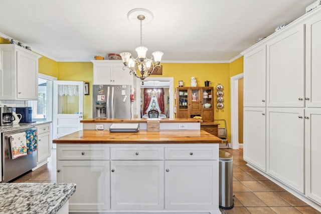 kitchen featuring stainless steel appliances, white cabinetry, and butcher block countertops