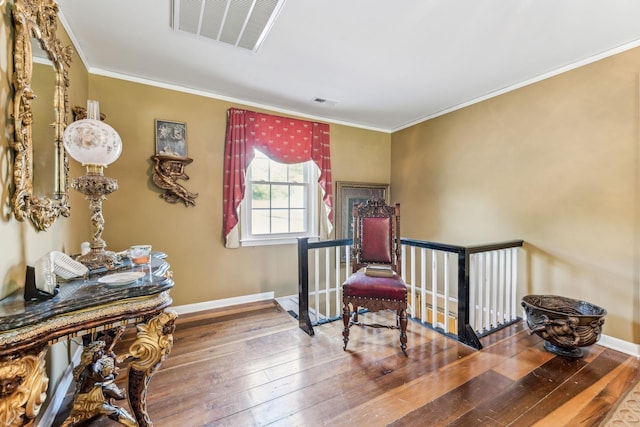 living area with wood-type flooring and crown molding