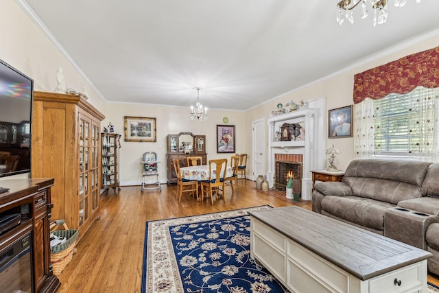 living room featuring a chandelier, light wood-type flooring, crown molding, and a brick fireplace