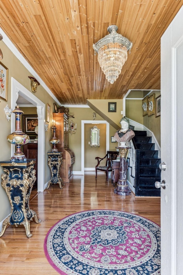 interior space featuring hardwood / wood-style floors, wooden ceiling, an inviting chandelier, and ornamental molding