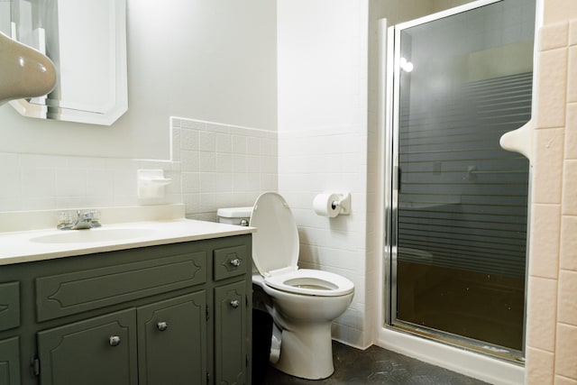 bathroom featuring vanity, toilet, tile walls, and a shower with shower door