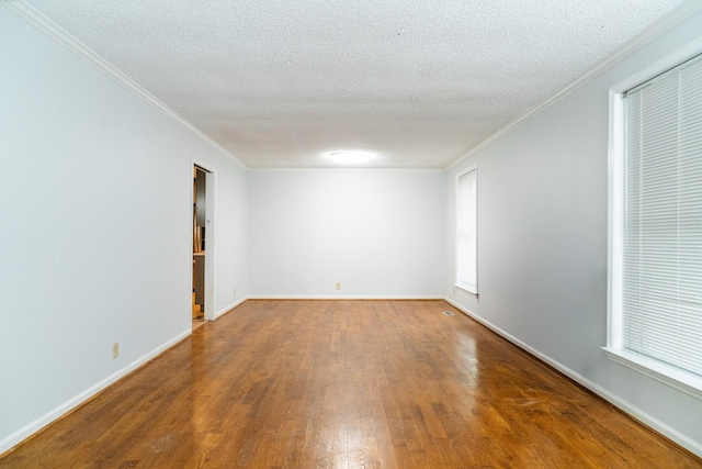 spare room with a textured ceiling, hardwood / wood-style flooring, a wealth of natural light, and ornamental molding