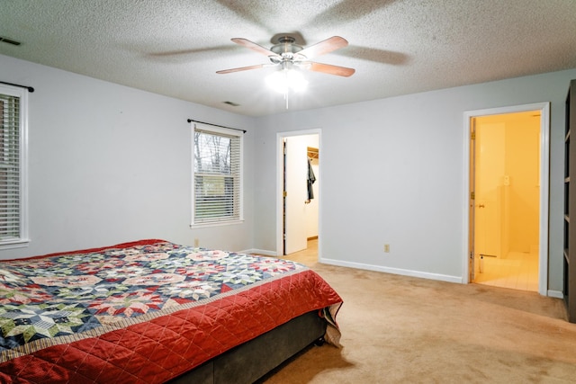 carpeted bedroom featuring ceiling fan, a textured ceiling, and ensuite bath