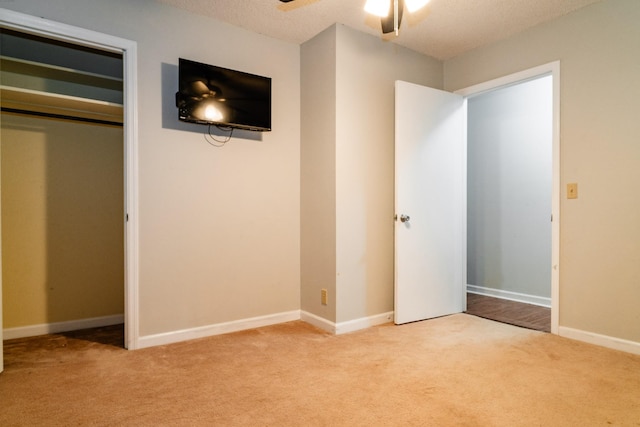 unfurnished bedroom featuring light carpet, a closet, ceiling fan, and a textured ceiling