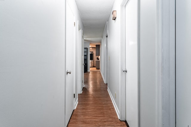 corridor featuring dark hardwood / wood-style flooring and a textured ceiling