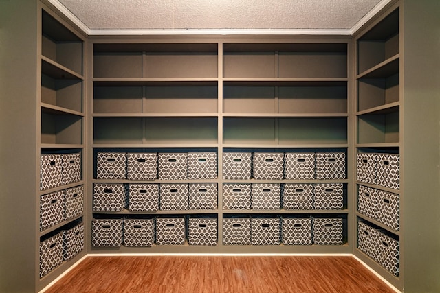 wine area with a textured ceiling, light wood-type flooring, and crown molding