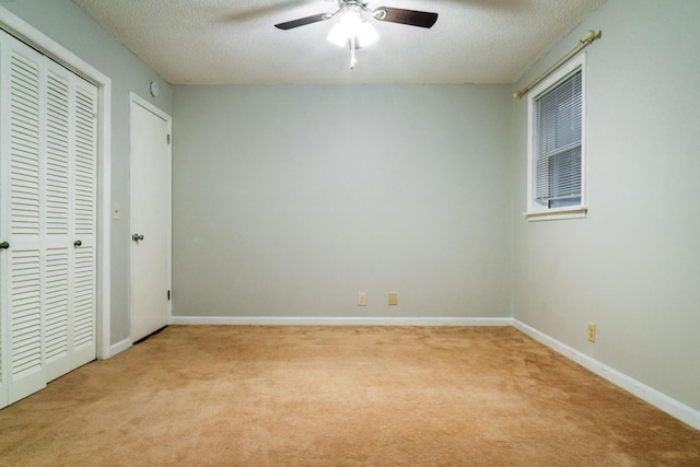 unfurnished bedroom with a textured ceiling, light colored carpet, and ceiling fan