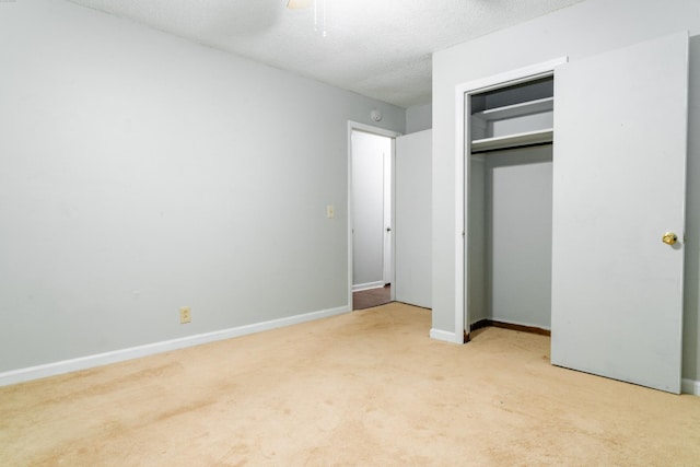 unfurnished bedroom with light carpet, a closet, ceiling fan, and a textured ceiling