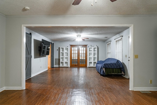 unfurnished bedroom with a barn door, a textured ceiling, and dark wood-type flooring