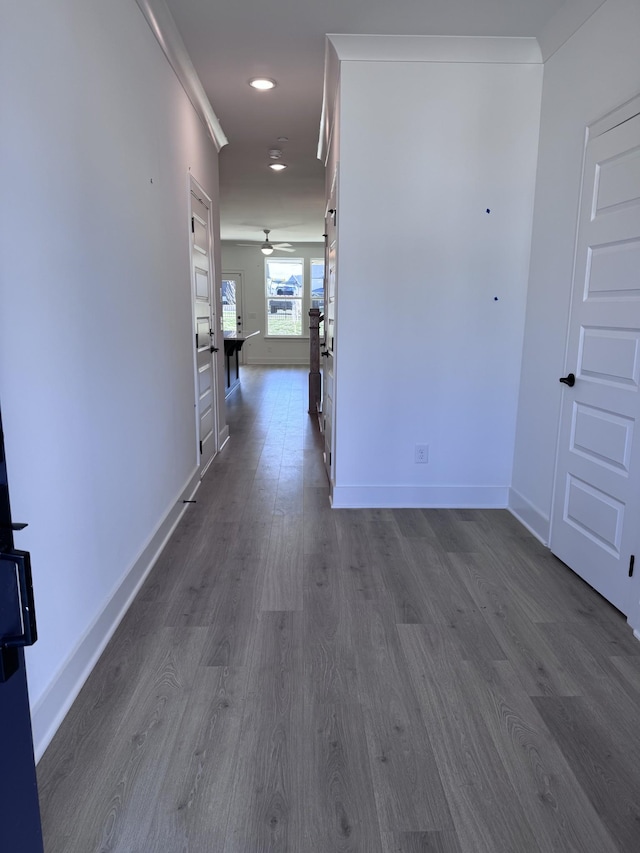 hall with ornamental molding, baseboards, and dark wood-style flooring