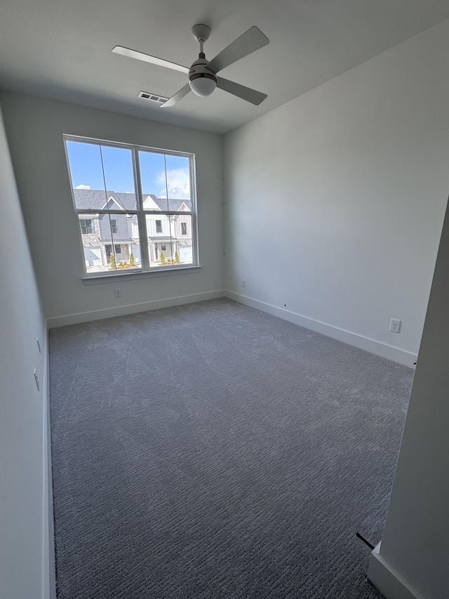 carpeted spare room with visible vents, baseboards, and a ceiling fan