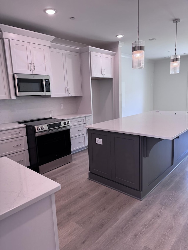 kitchen featuring a kitchen island, pendant lighting, light wood-style floors, white cabinets, and stainless steel appliances