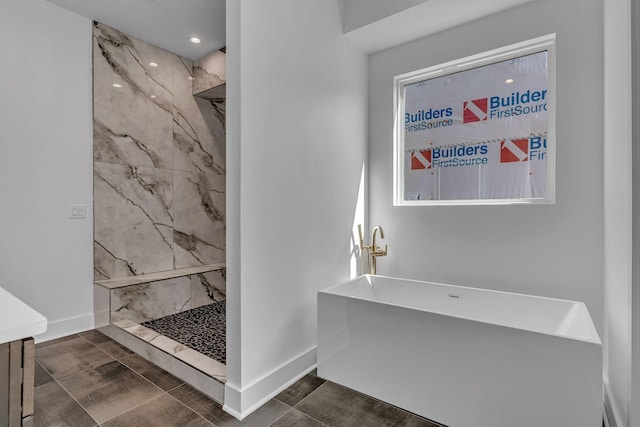 bathroom featuring a marble finish shower, vanity, and baseboards