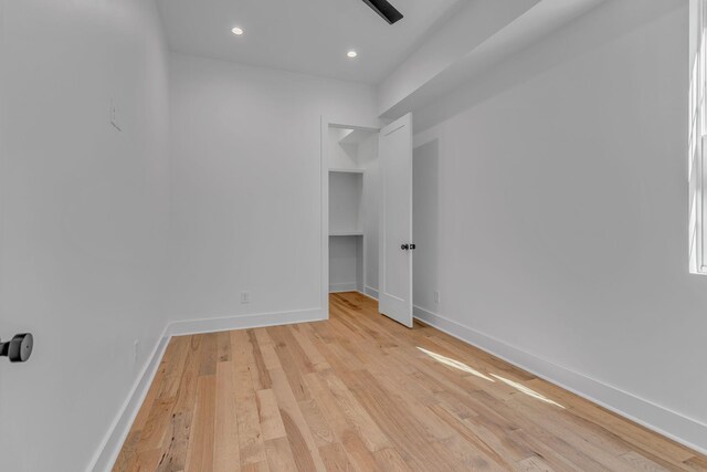 unfurnished bedroom with recessed lighting, light wood-style flooring, and baseboards