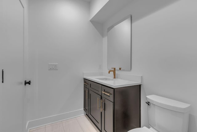 half bath with toilet, tile patterned floors, vanity, and baseboards