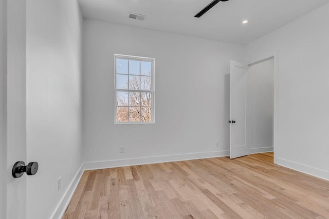 empty room featuring a ceiling fan, visible vents, light wood-style flooring, and baseboards